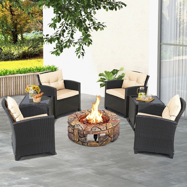 a fire pit sitting on top of a patio next to chairs and a potted plant