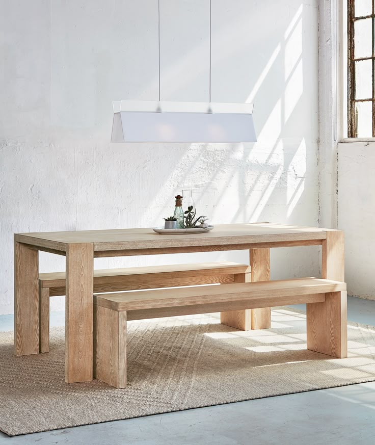 a wooden table with two benches in front of it and a light fixture hanging from the ceiling