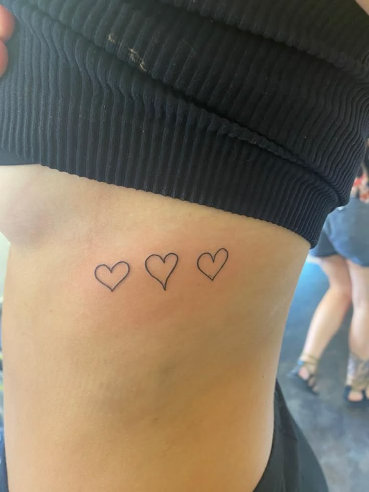 the back of a woman's stomach with three small hearts on her left side