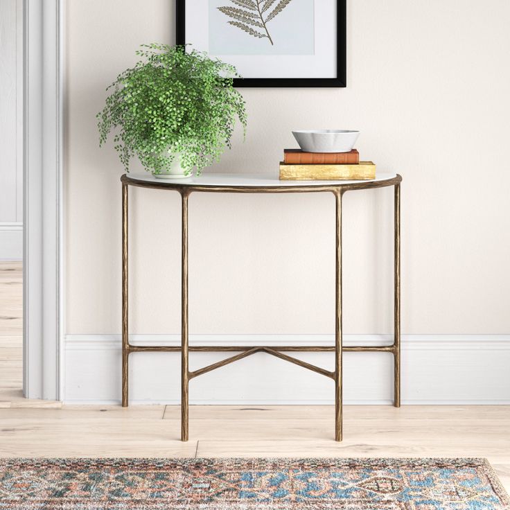 a table with a plant on it in front of a white wall and a rug