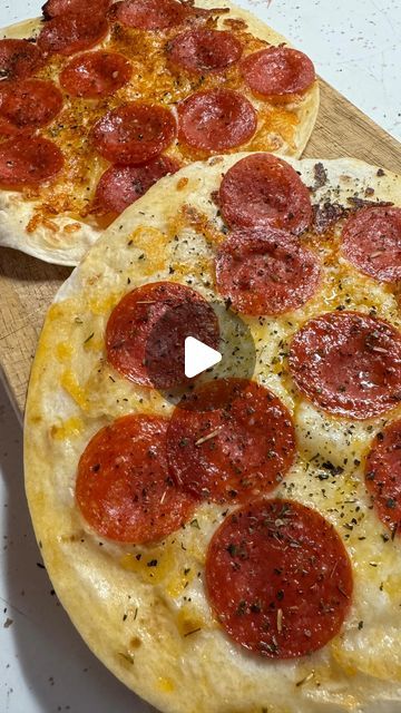 two pepperoni pizzas sitting on top of a cutting board next to each other