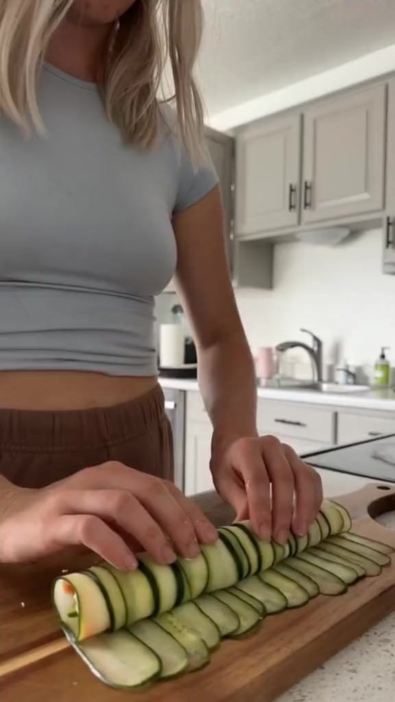 a woman is slicing cucumbers on a cutting board