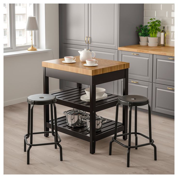 a kitchen island with two stools and a cutting board on the bottom shelf in front of it