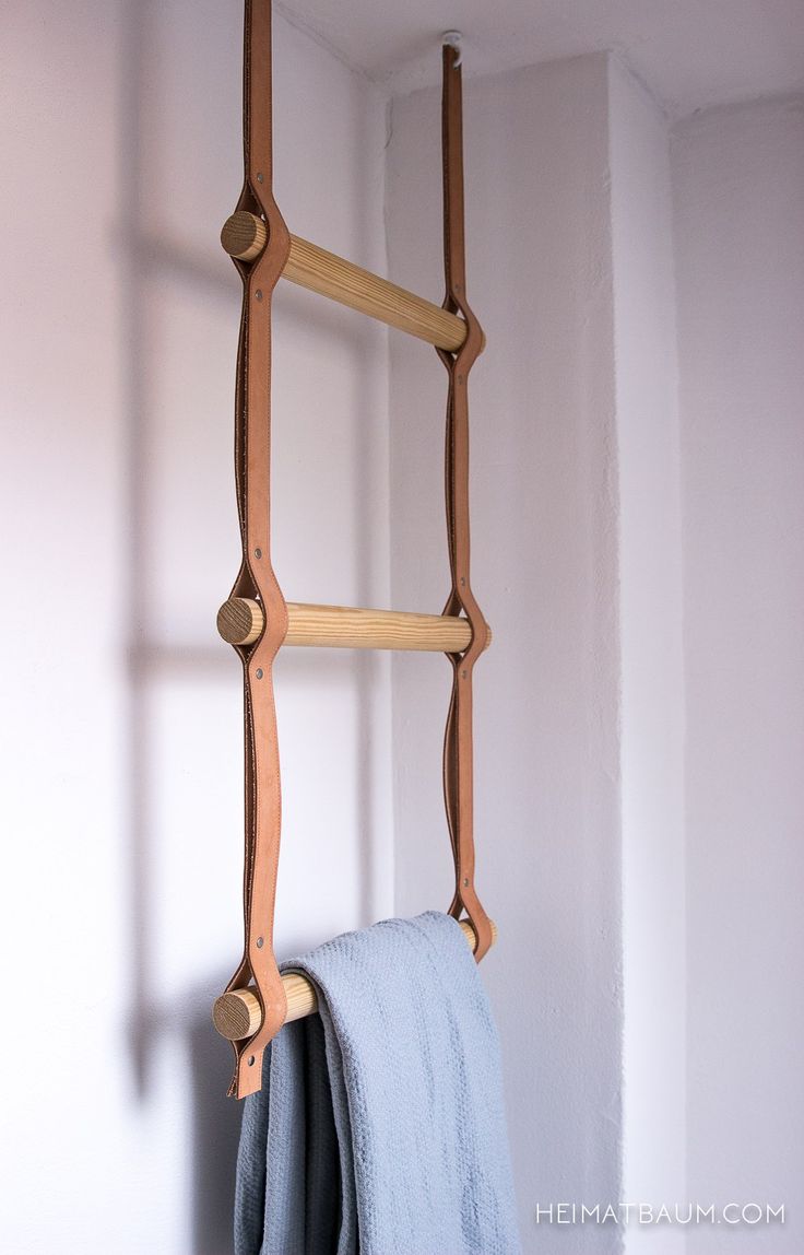 a wooden ladder hanging from the side of a wall next to a blue towel rack