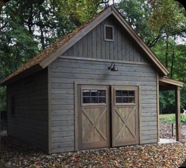 an outdoor storage shed with two doors on the front and one door open, surrounded by leaves