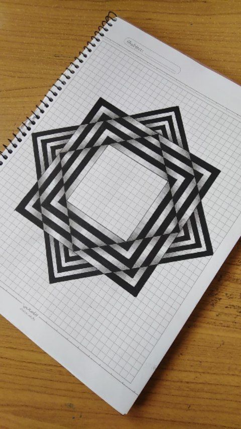 an open spiral notebook with black and white squares on the cover, sitting on top of a wooden table