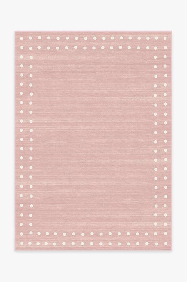 a pink area rug with white dots on the top and bottom corner, in front of a white wall