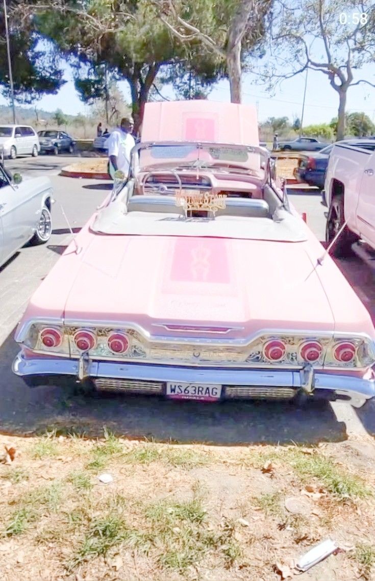 an old pink car parked in a parking lot