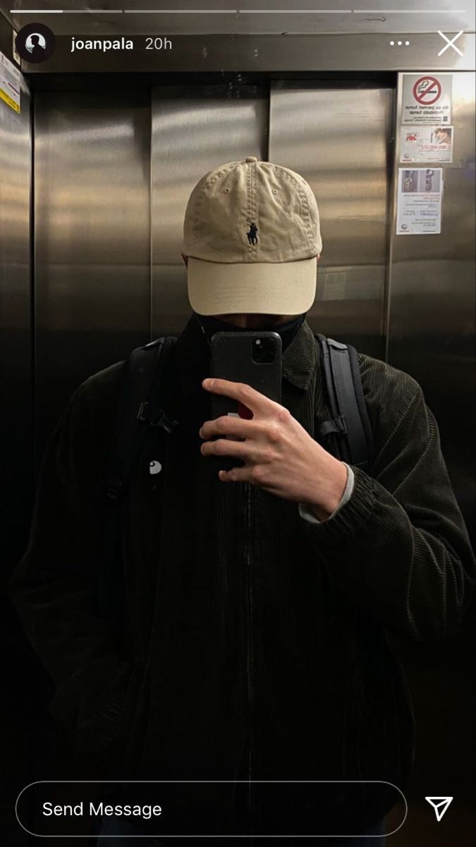 a man with a hat on taking a selfie in front of an elevator door