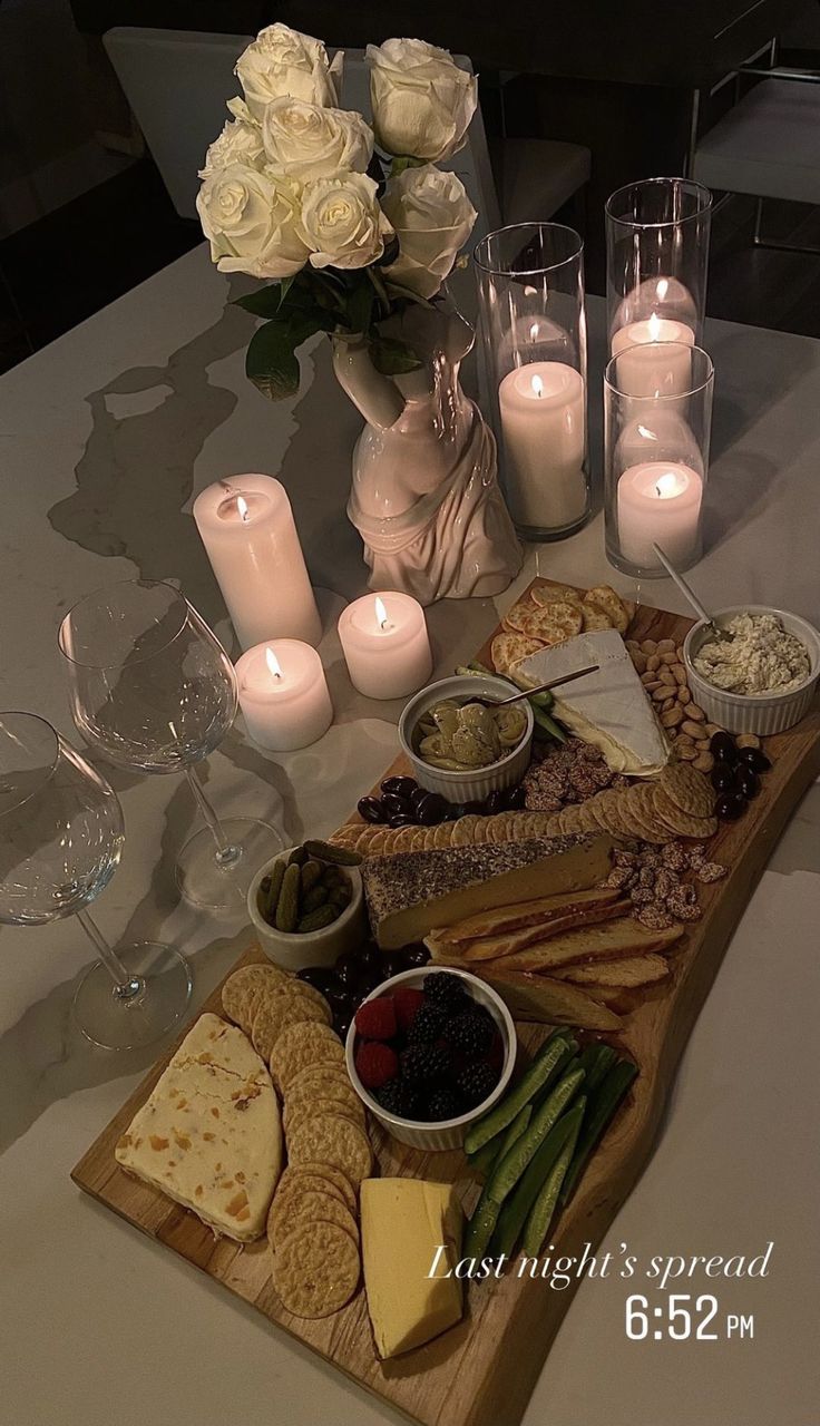 a table topped with wine glasses and plates filled with cheese, crackers and vegetables