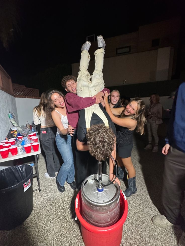 a group of people standing around each other in the middle of a room with one person upside down