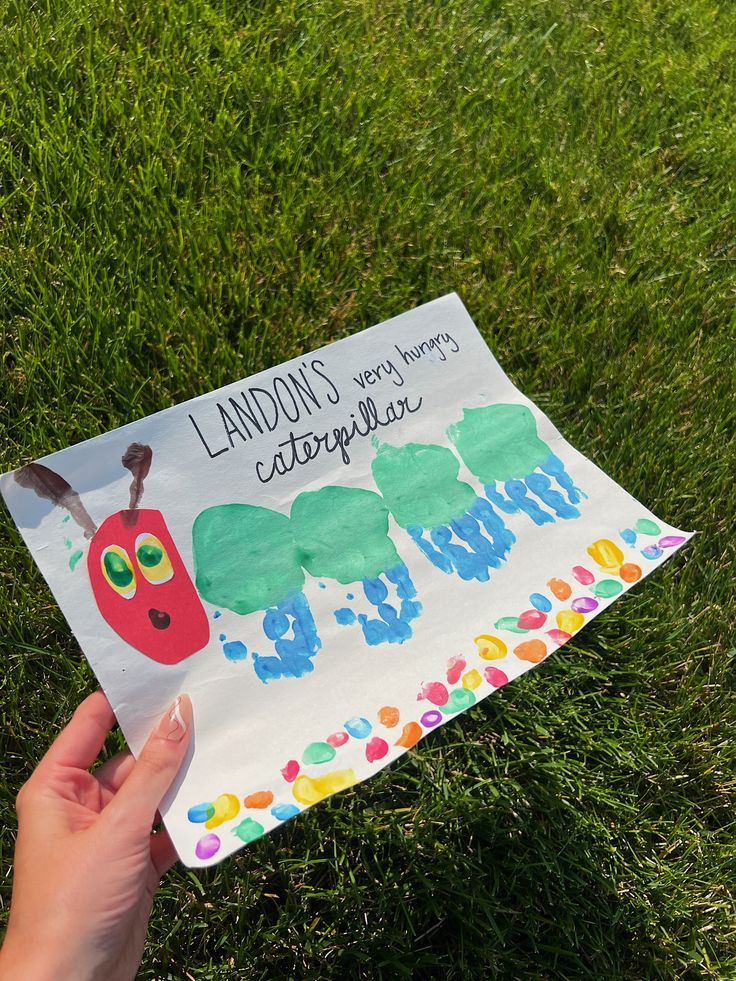 the very hungry caterpillar handprinted card is held in front of someone's face