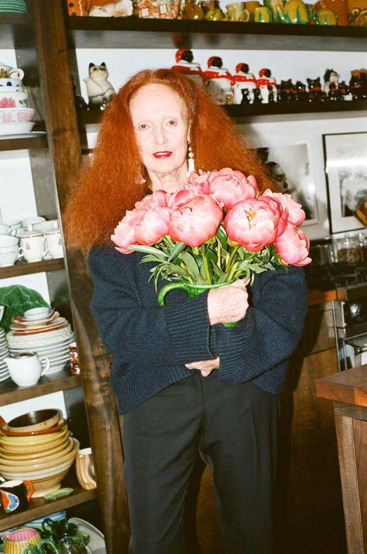 a woman with red hair holding flowers in her hands