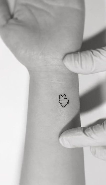 a person's wrist with a small heart tattoo on the left side of their arm