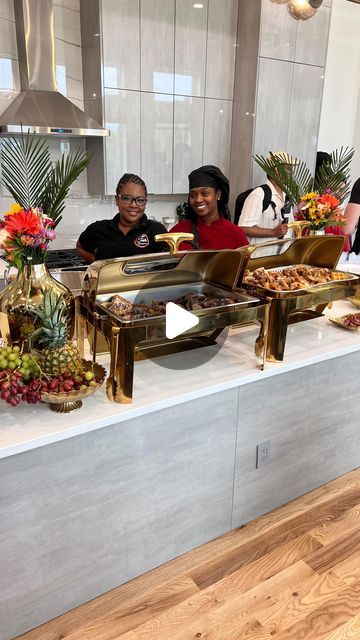 three people standing behind a buffet with food on it