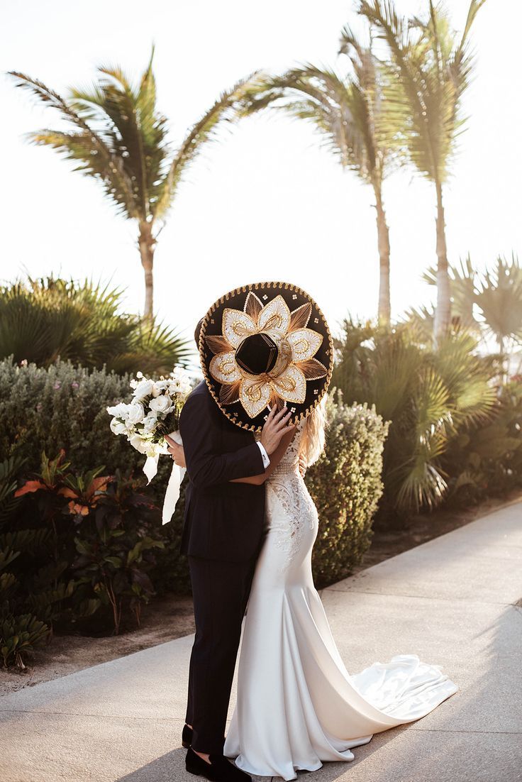 a bride and groom kissing in front of palm trees at their wedding day with the sun shining on them