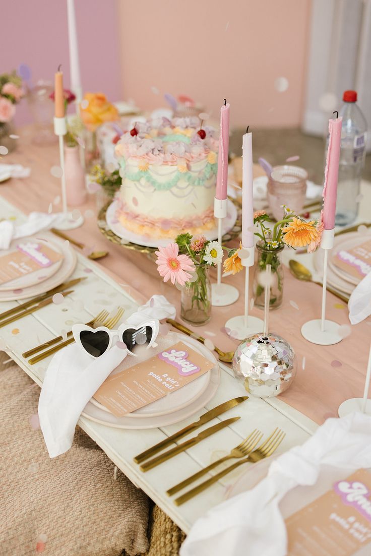 the table is set with pink and gold plates, napkins, and cake on it