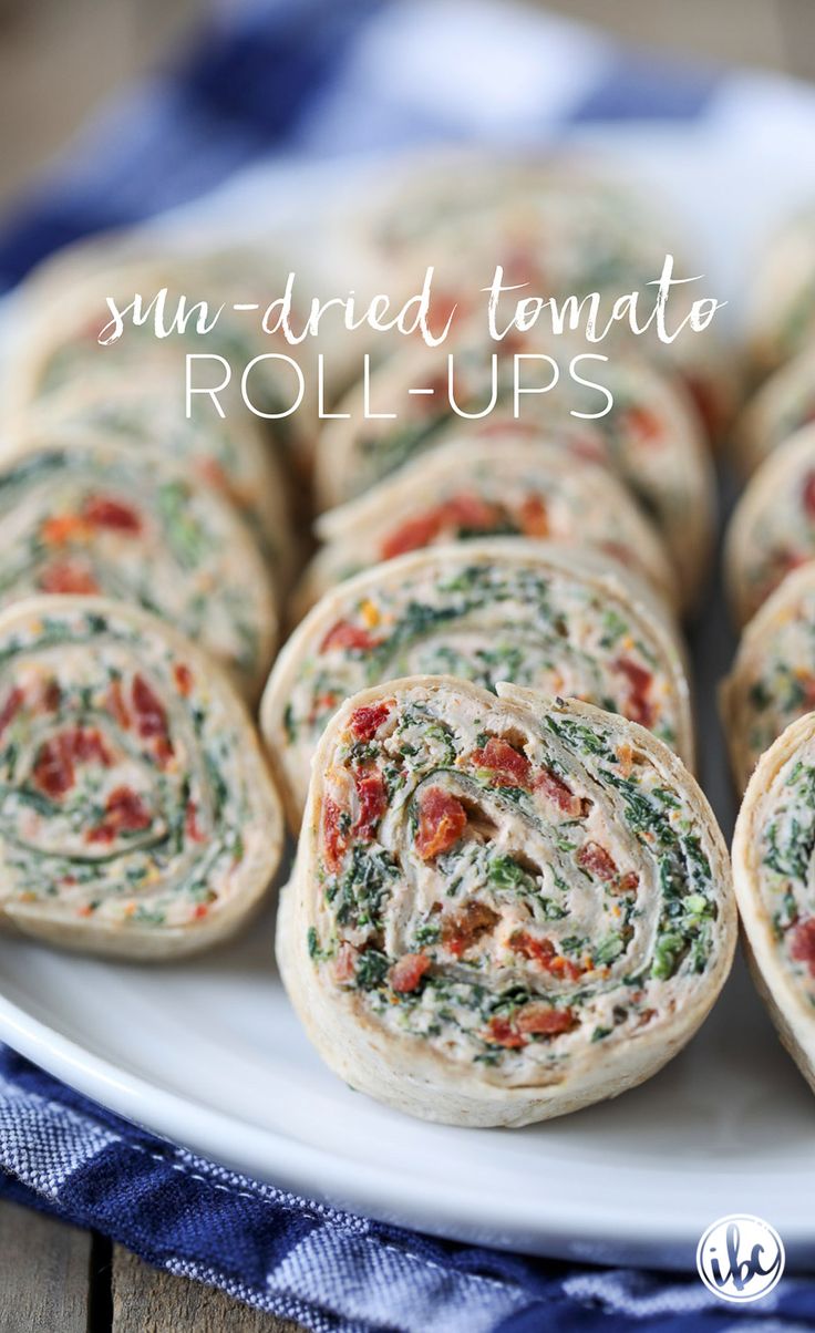 spinach and tomato roll ups on a white plate