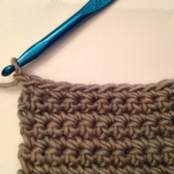 the crochet stitch is being worked on with a blue handled knitting needle,