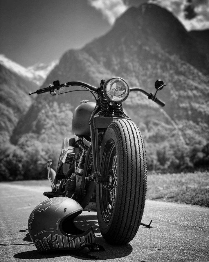 a motorcycle parked on the side of a road with mountains in the backgroud