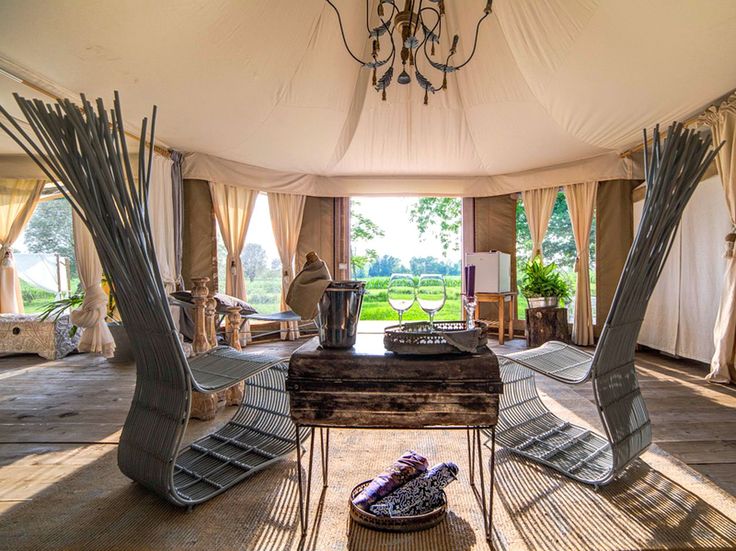 the inside of a tent with chairs, tables and lamps hanging from it's ceiling