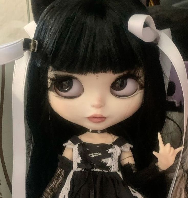 a close up of a doll with long black hair and big eyes wearing a dress