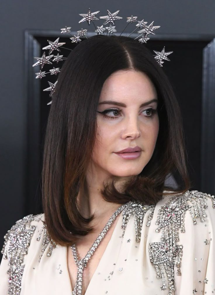 a woman with long hair wearing a tiara and pearls on top of her head