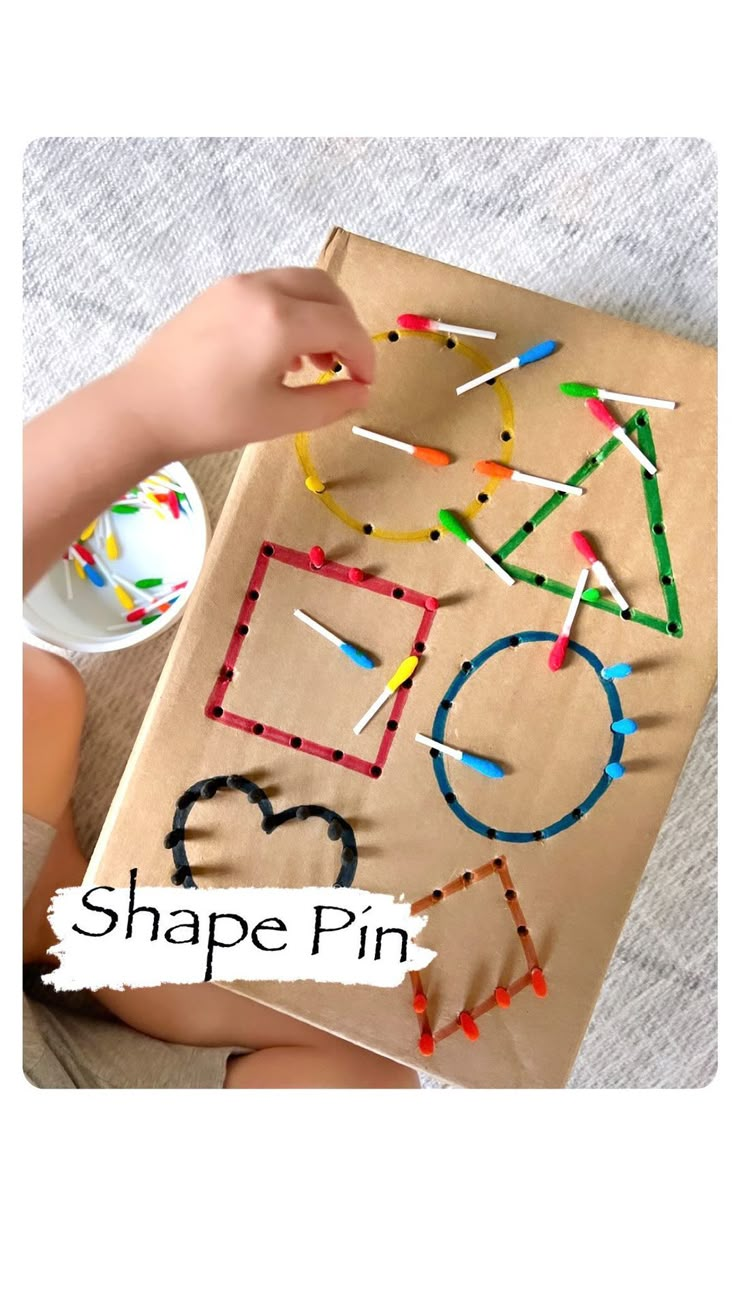 someone is making a shape pin craft with colored sticks and glue on the cardboard box