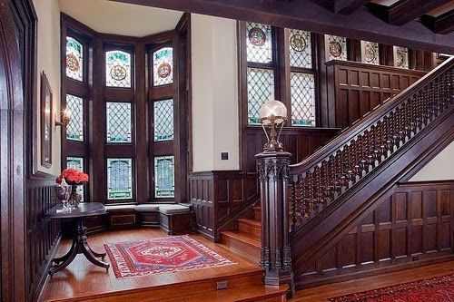 an ornate entryway with wood paneling and stained glass windows on the second floor