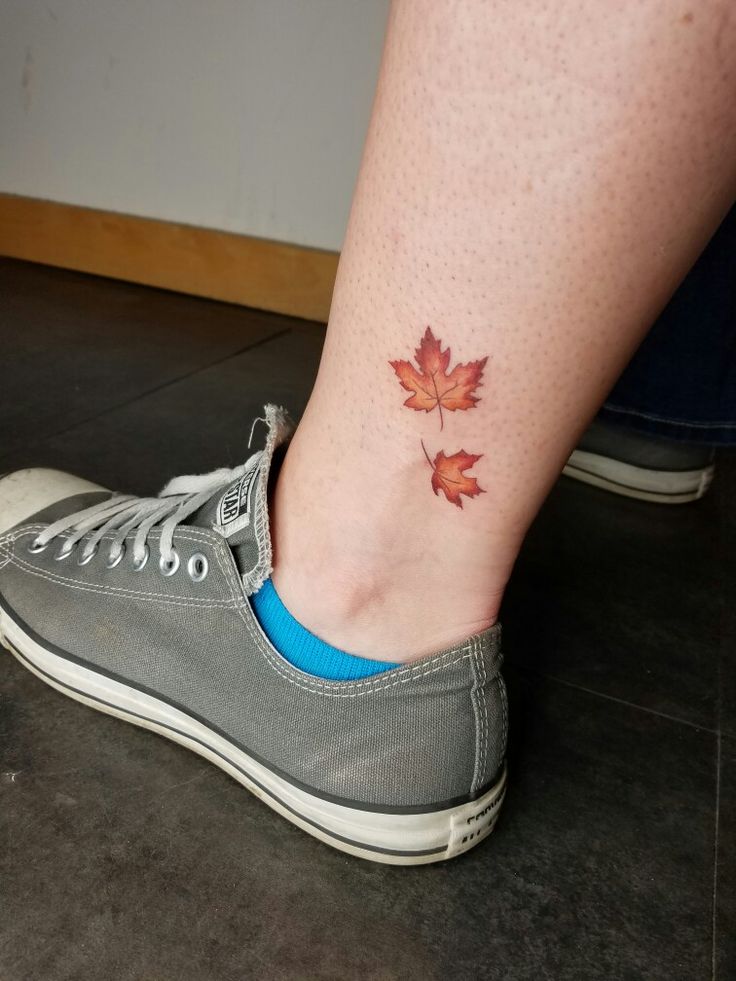 a woman's foot with a small maple leaf tattoo on her left side ankle