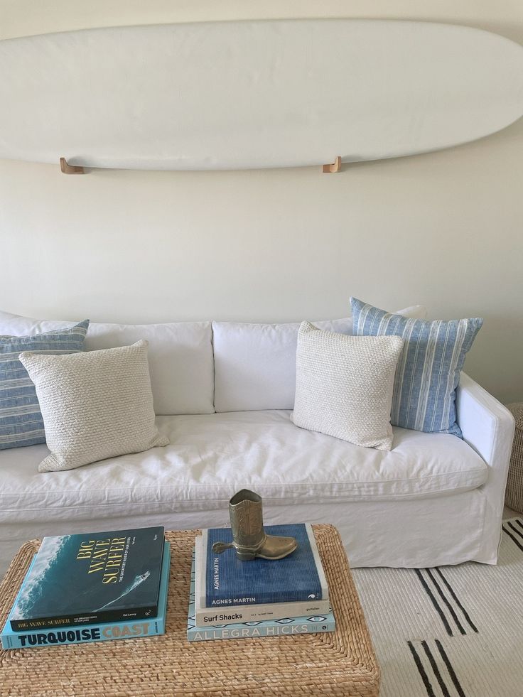 a living room with a white couch and a surfboard on the wall above it