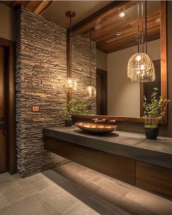 a bathroom with stone walls and lights hanging from it's ceiling, along with a bowl on the counter