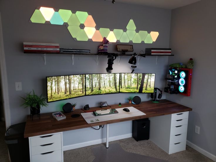 a desk with two monitors on it and some lights hanging from the ceiling above them