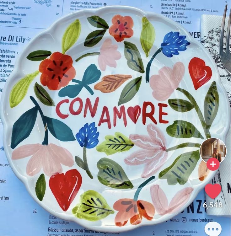 a decorative plate with the word conamore painted on it and flowers in different colors