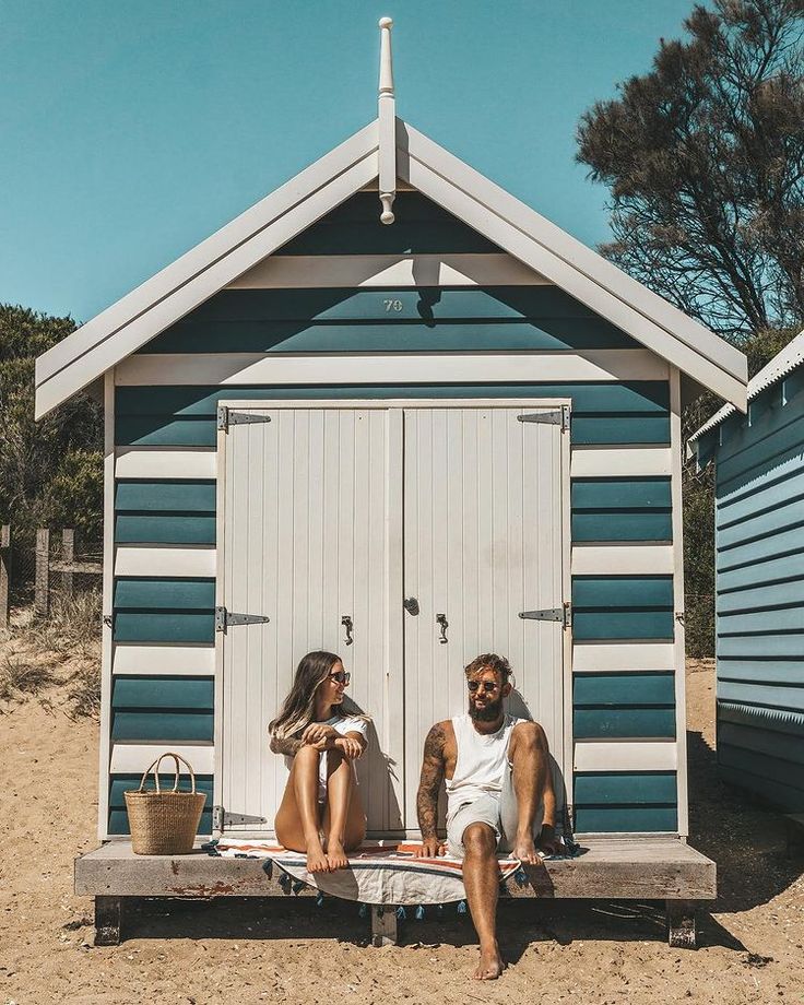 two people sitting on a bench in front of a shed