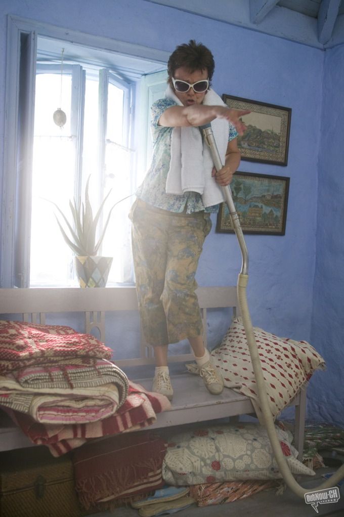 a woman is cleaning the bed in her room with a mop and some pillows