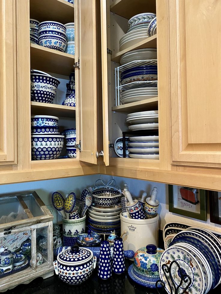 blue and white dishes are stacked on wooden cabinets