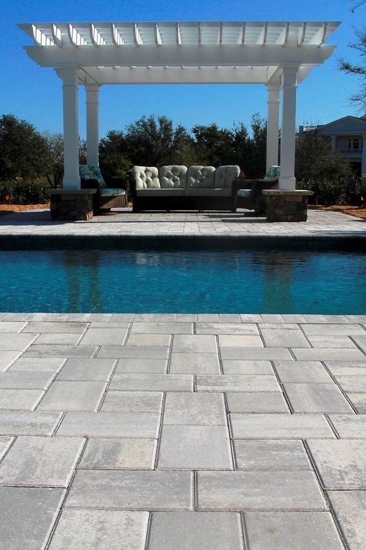 an outdoor patio with a couch next to a pool and pergolated seating area