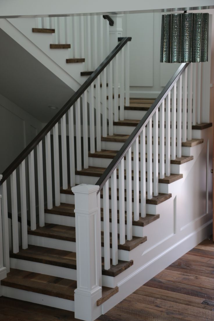 there is a white stair case in the house with wood floors and handrails