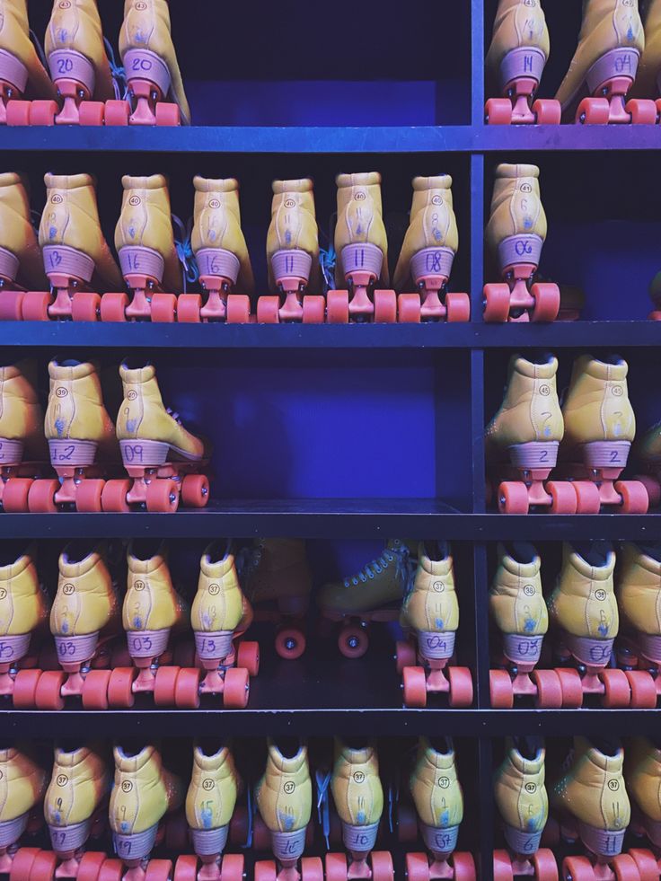 several rows of skateboards and roller skates in front of a blue shelf with red wheels