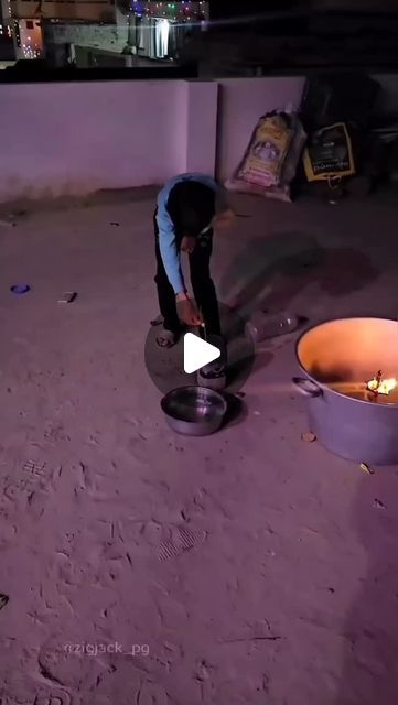 a man is bending over to put something on the ground in front of two buckets