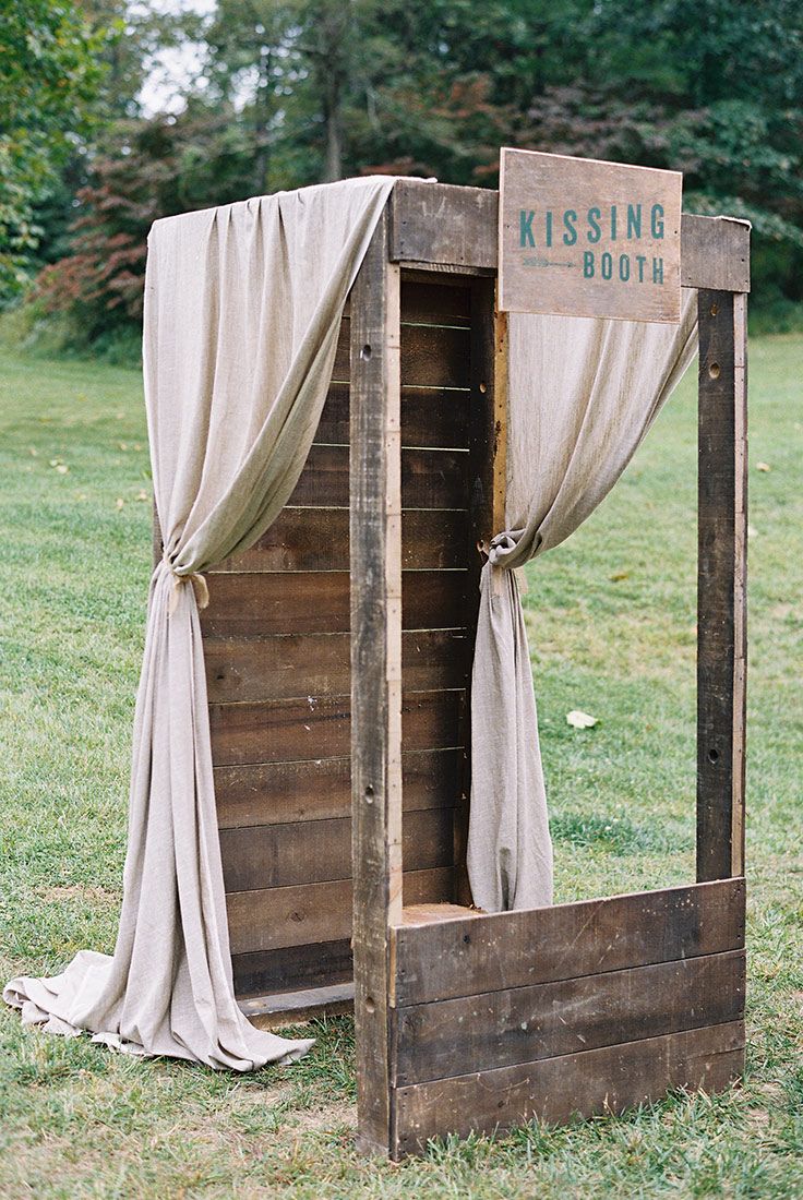 an old wooden box with drapes on the sides and a sign that says kissing booth