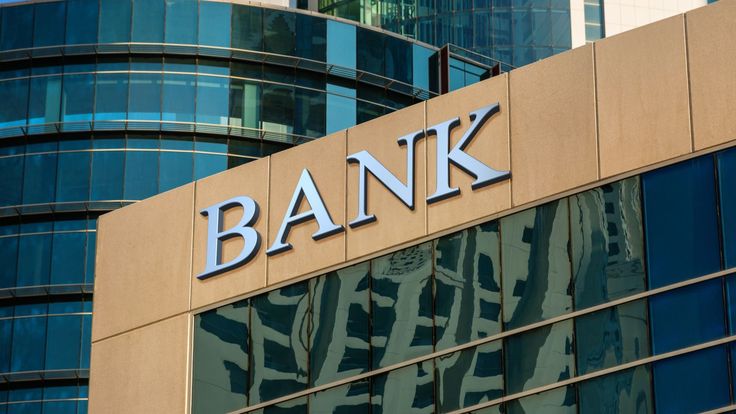 the bank sign on top of a building in front of some glass and metal windows