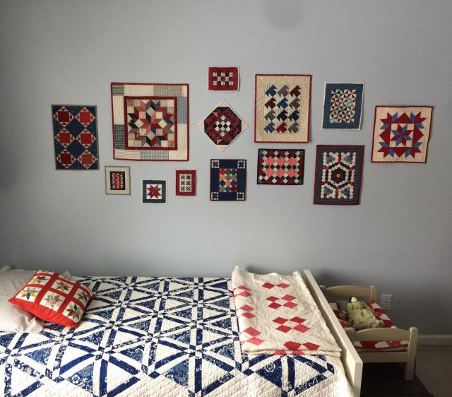 a bed with many quilts on the wall above it