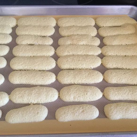 several rows of uncooked bread on a baking sheet