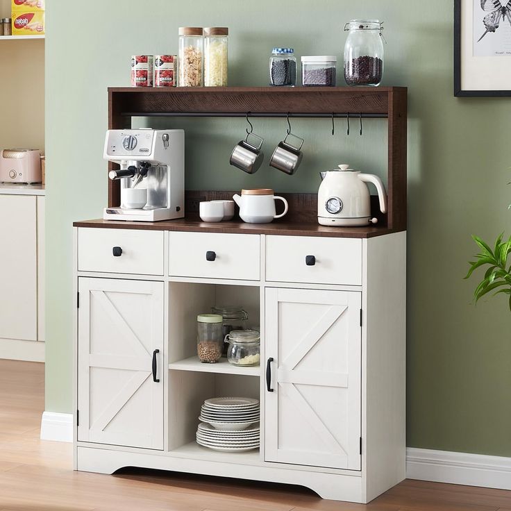 a kitchen with green walls and white cupboards filled with dishes on top of it