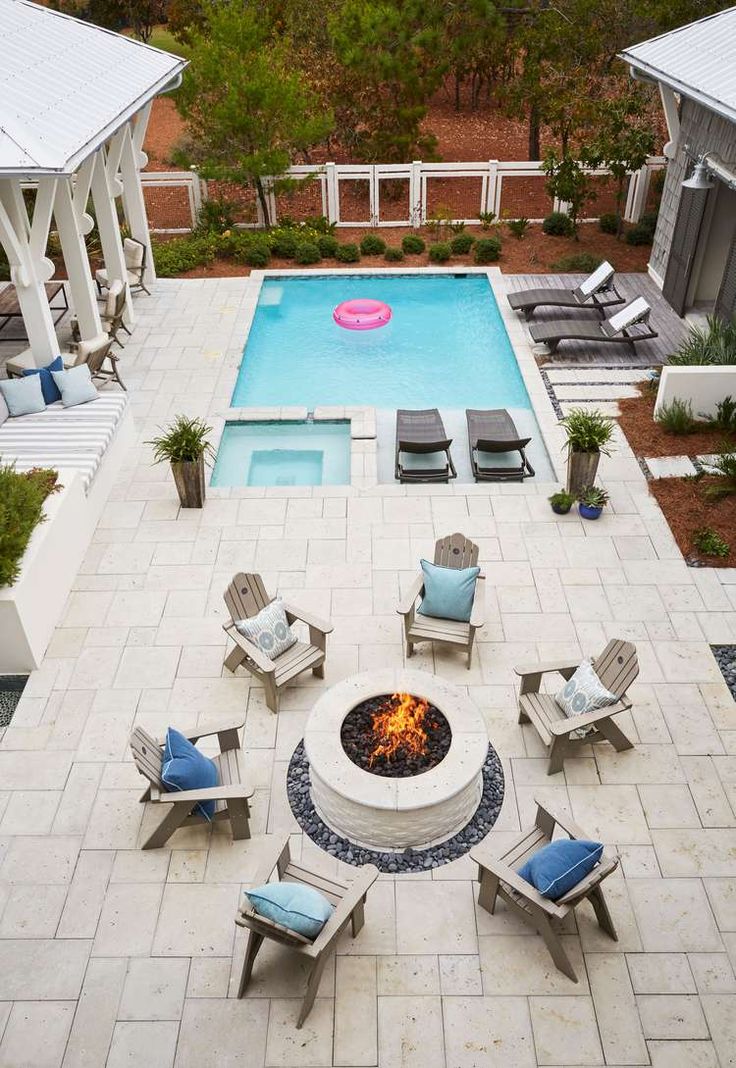 an aerial view of a fire pit surrounded by lawn chairs and loungers next to a swimming pool