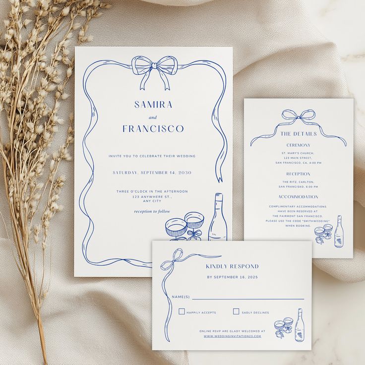 the wedding stationery is laid out on top of white fabric and features blue ink