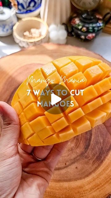 a person holding a piece of mango on top of a wooden cutting board with the words, 7 ways to cut mangoes