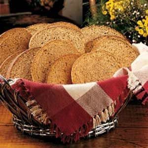 a basket filled with lots of bread on top of a wooden table next to flowers